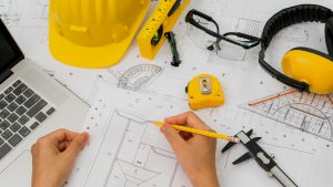  >thisisjustarandomplaceholder<Construction plans with yellow helmet and drawing tools on bluep | Iberian Press® 
