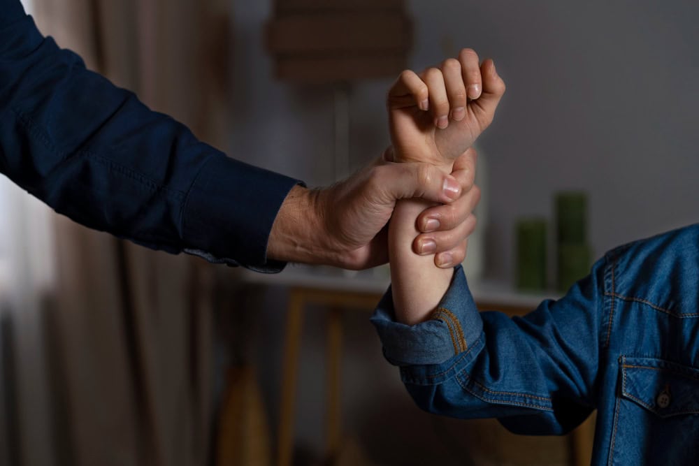 775781 – Kika Fumero Adult hand firmly holding a child's forearm in a home setting, suggesting guidance or safety support.